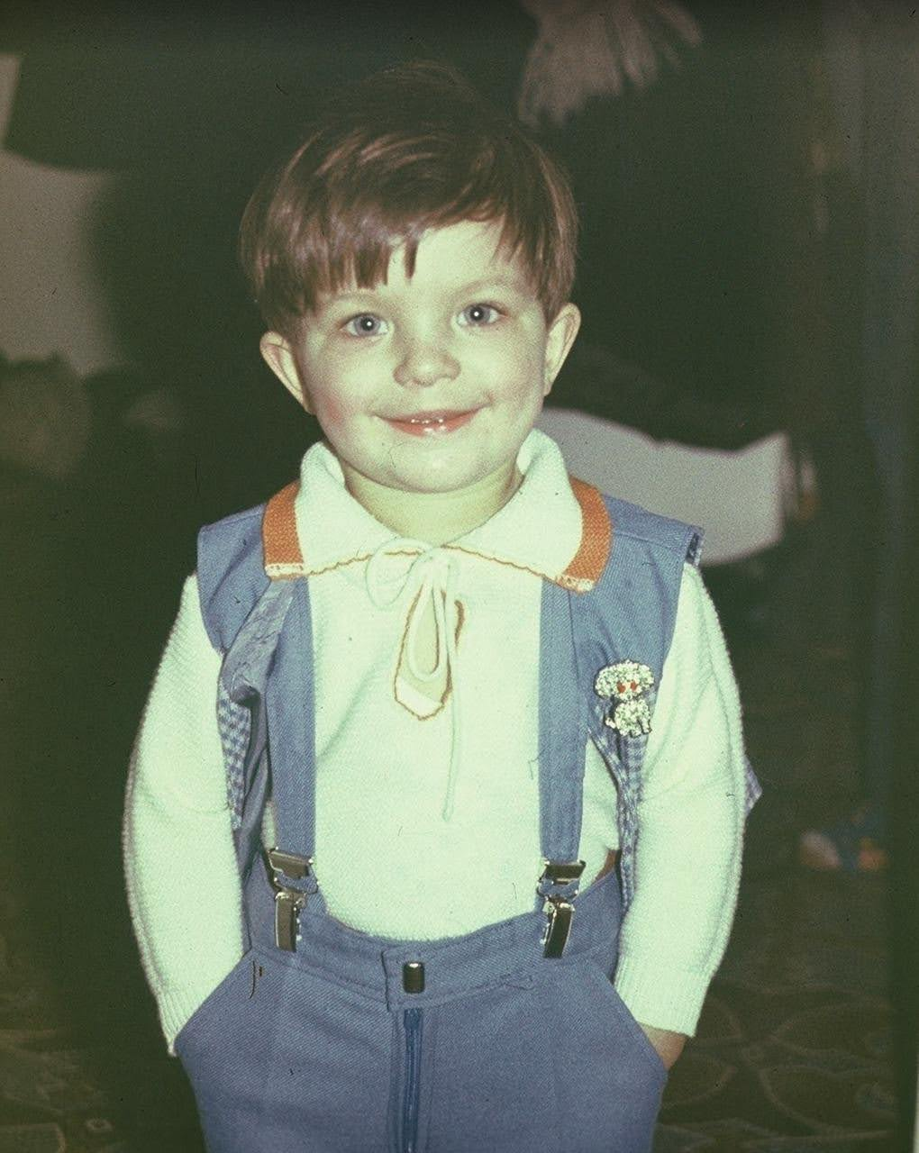 Denis as a young child, smiling at the camera