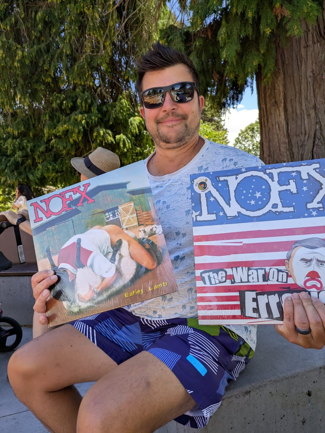 Denis smiling and holding two NOFX records